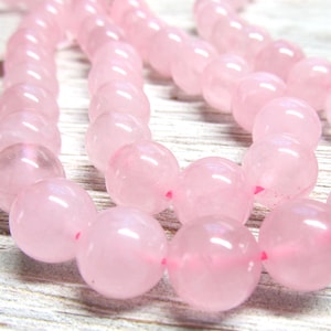 Puede incluir: Una hebra de cuentas de cuarzo rosa. Las cuentas son redondas y lisas, y tienen una apariencia translúcida.