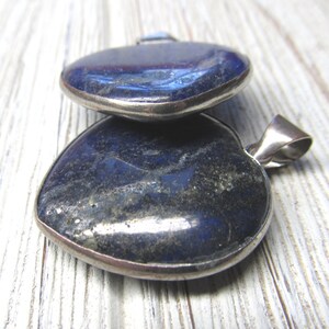 Puede incluir: Dos colgantes en forma de coraz&oacute;n hechos de piedra lapisl&aacute;zuli azul oscuro con engastes de plata.