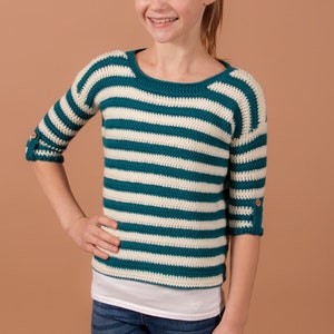 A cute girl rocking a trendy striped crochet sweater, adding a touch of fashion to her look.