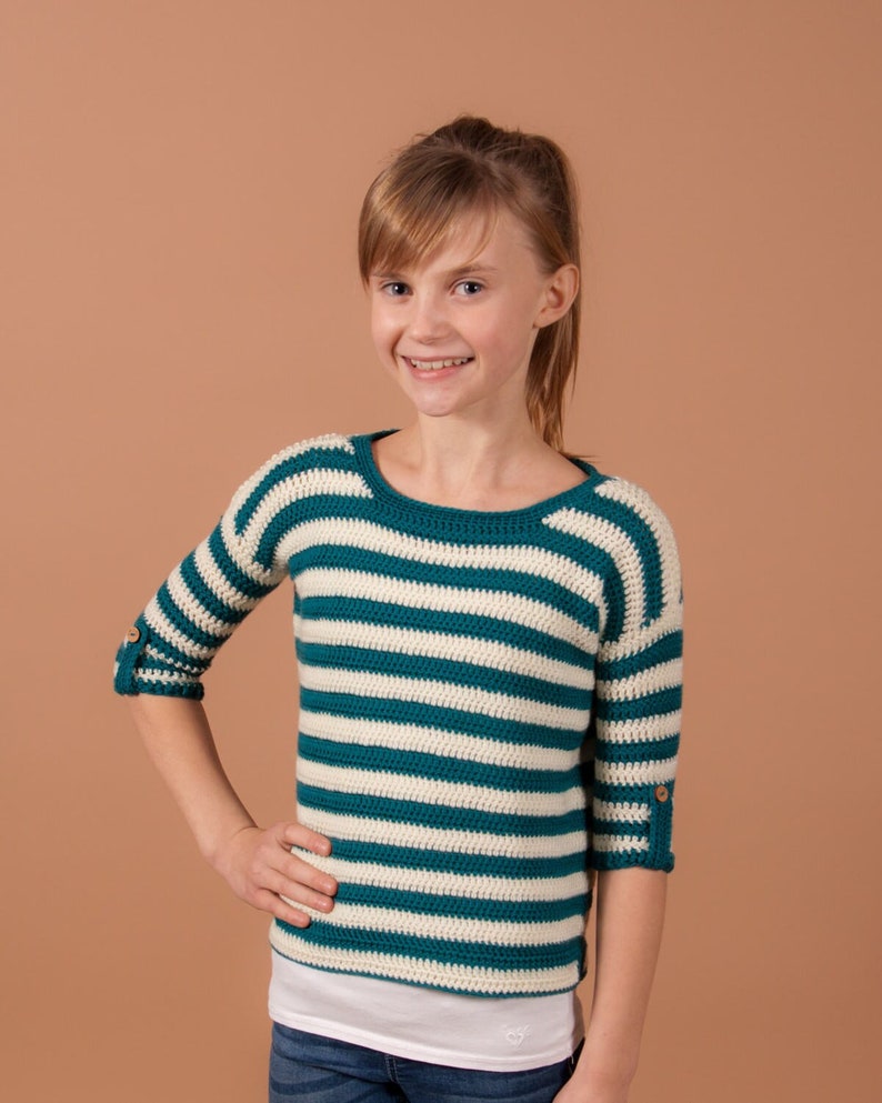 A cute girl rocking a trendy striped crochet sweater, adding a touch of fashion to her look.