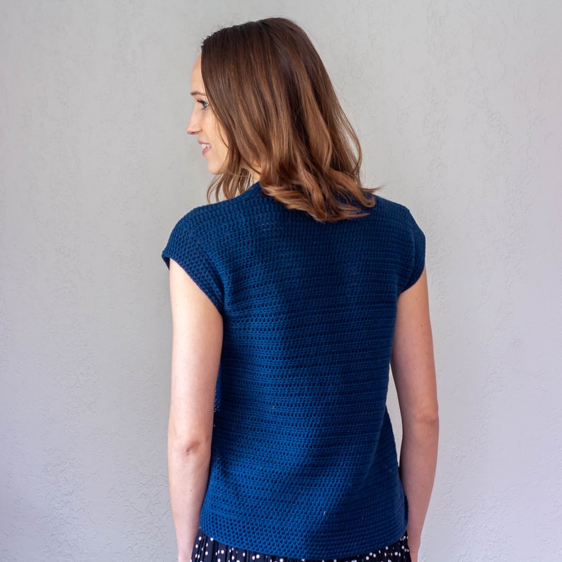 May include: A blue crocheted sleeveless top with a textured pattern. The top is cropped and has a relaxed fit.