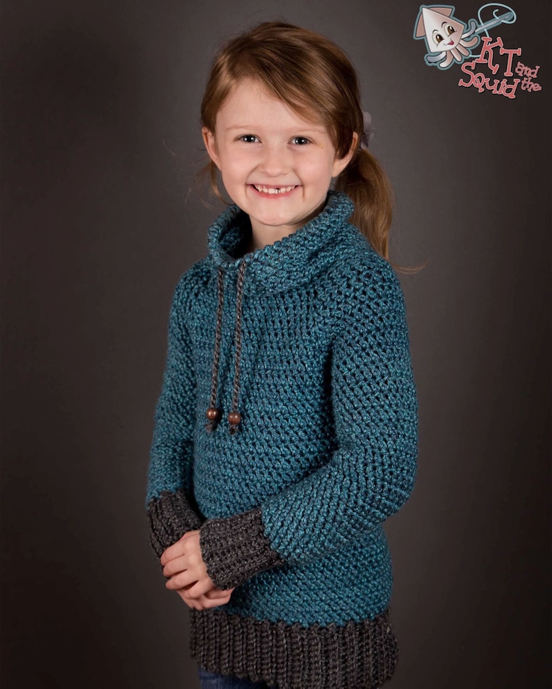 A young girl with a warm smile, dressed in a cozy blue crochet sweater.