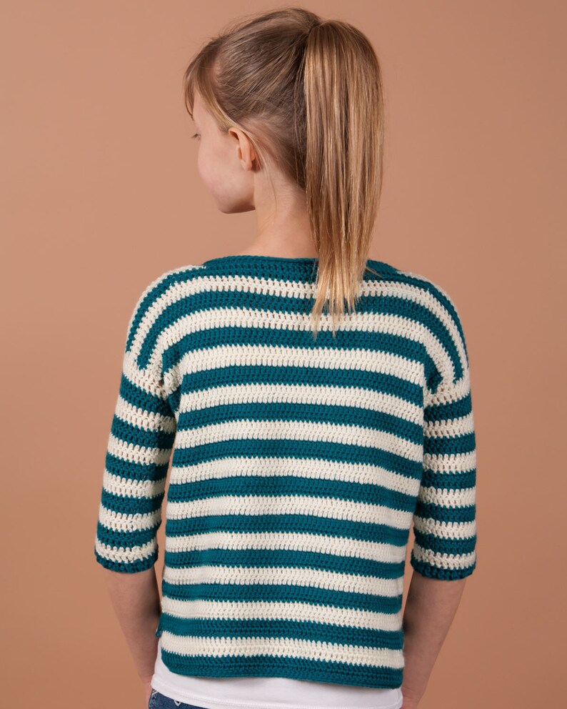 An adorable girl with a vibrant striped crochet sweater, showcasing her playful and fashionable side.