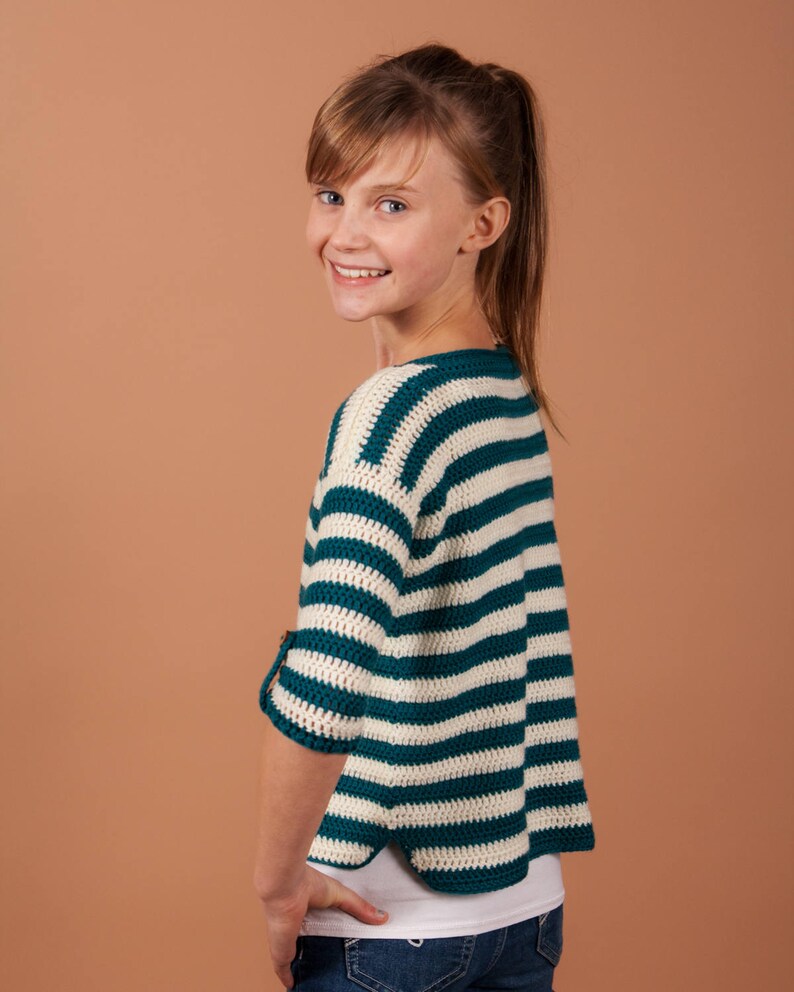 A cheerful young girl in a striped crochet sweater, radiating warmth and style.