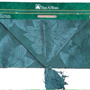 May include: Teal damask table runner with a tassel fringe. The runner features a floral design and the text "Trim A Home. Damask Table Runner".
