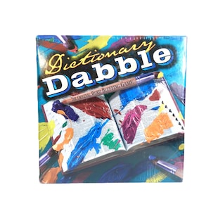 May include: A boxed board game titled "Dictionary Dabble: The Original Word Bluffing Game." The box features a colorful design with an open book, paintbrushes, and paint splatters in various colors. The game is sealed in plastic.