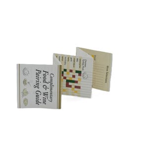 May include: Three small, folded booklets with cream-colored covers and pages. The booklets display text including "Complimentary Food & Wine Pairing Guide" and "Wine Selections." One page shows a color-coded food and wine pairing chart.