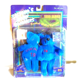 May include: Two blue plush bear toys in a plastic package. Each bear has a red number 19 on its chest. One bear has "GONZAL" on its chest. The packaging reads "1999 SERIES Baseball Hall of Bamamers".