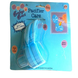 May include: A blue plastic pacifier case with the words "Baby's Best Pacifier Care" and "Buy 1 Get 1 Free" on the packaging. The case is designed to hold and sanitize pacifiers.