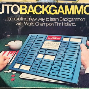 May include: A blue and white board game called "Auto Backgammon" with the text "Game 14 Novice Series by Tim Holland". The game board is made of plastic and has a series of slots for cards. The game is designed to teach players how to play backgammon.