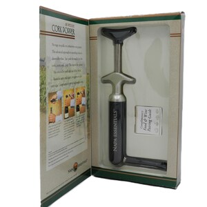 May include: A boxed Napa Essentials cork popper. The wine opener is silver and black, with the words "NAPA ESSENTIALS" printed on the side. The box includes a food and wine pairing guide.