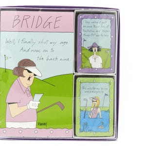 May include: A boxed set of Bridge cards with a golf theme. The box features a cartoon illustration of a golfer and text that reads "BRIDGE". Two additional cards show golfers with humorous captions. The box is purple and white.