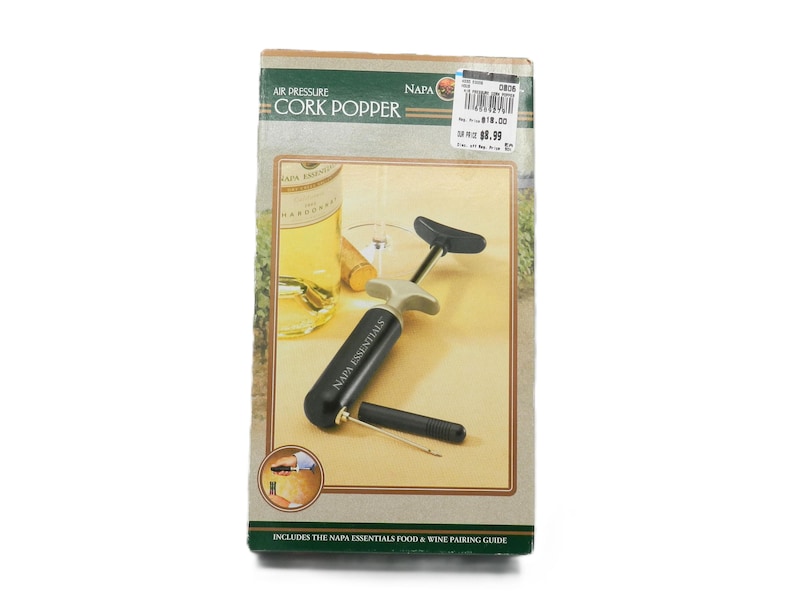 May include: A boxed air pressure cork popper. The box features an image of a wine bottle, a wine glass, and the cork popper. The text on the box reads "Air Pressure Cork Popper" and "Napa Essentials".