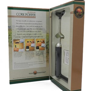 May include: A boxed Napa Essentials air pressure cork popper. The box is tan and green with text and illustrations. The cork popper is silver and black. The text on the box reads "Air Pressure Cork Popper".