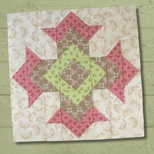 May include: A quilt block with a brown, green, and pink floral pattern. The block is made up of squares and triangles, and the design is symmetrical.