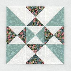 May include: A square quilt block featuring a patchwork design. The block is composed of white, teal, and floral print triangles. The floral print includes pink, yellow, and blue flowers on a dark background. The teal fabric has a white floral pattern.