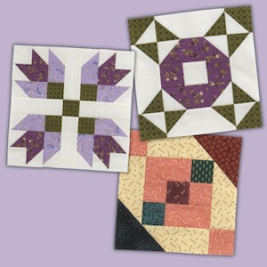 May include: Three square fabric quilt blocks featuring geometric patterns. One block displays purple floral and olive green squares on white. Another shows a purple floral ring with olive green triangles. The third features peach, dark green, and black.