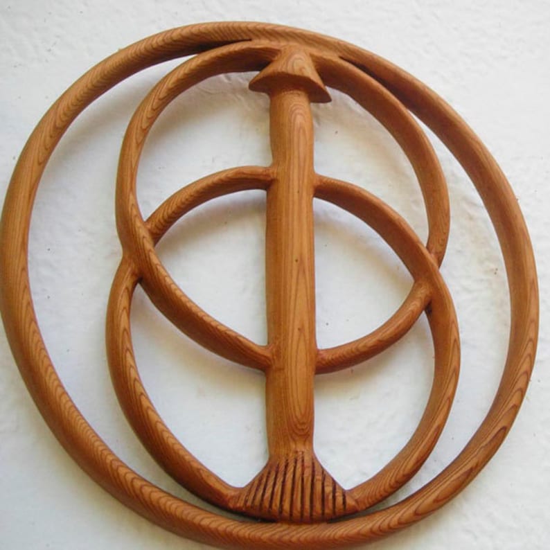 May include: A wooden sculpture featuring three concentric circles and a central vertical post. The sculpture is crafted from light brown wood and has a natural wood finish.
