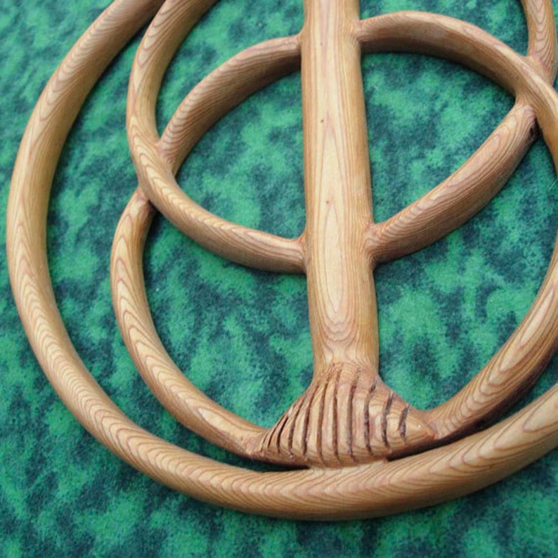 May include: A wooden carving of a tree of life with concentric circles, the bottom of the tree trunk is carved with a detailed pattern.