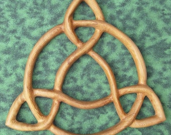 May include: A wooden Celtic knot, also known as a Trinity knot, carved in a light brown color. The knot is a symbol of interconnectedness and eternity.