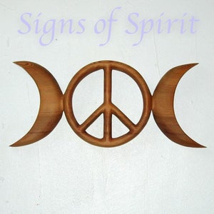 May include: A wooden wall hanging with a triple moon symbol and a peace sign in the center. The symbol is carved from wood and has a natural brown color.