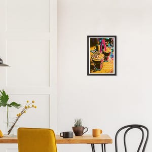 May include: A framed print featuring two iced coffee drinks with whipped cream and straws. The print has a black frame and the text "No Filter" and "A pause between distractions". The image has a colorful, artistic style.