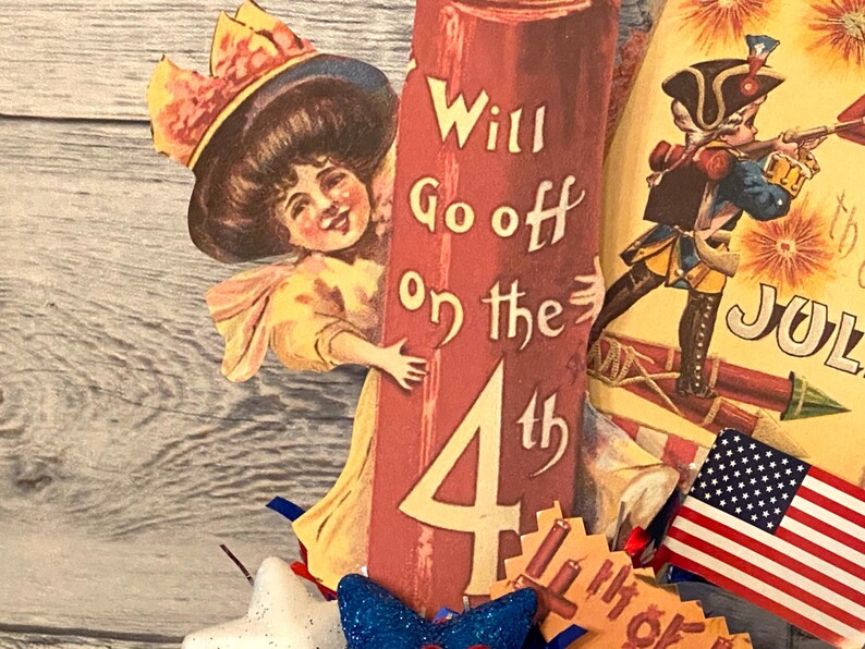 May include: Vintage patriotic Fourth of July decoration featuring a smiling girl, a soldier, and an American flag. The red pillar reads "Will Go off on the 4th". Includes a blue bow and star.