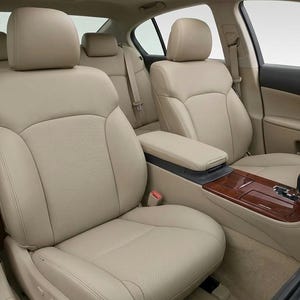 Puede incluir: El interior de un vehículo con asientos de cubo de cuero beige con paneles centrales perforados, reposacabezas ajustables y cinturones de seguridad. La consola central incluye un acabado de madera oscura, palanca de cambios y compartimento.