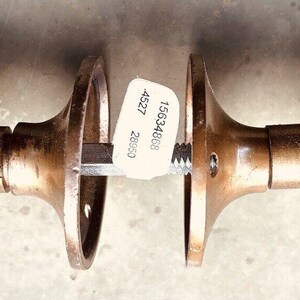May include: A pair of antique brass door knobs with intricate floral designs. The knobs are attached to a metal rod and have a label with the text "156346W 4527 20000".