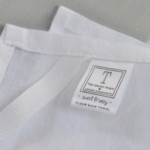 Pu&ograve; includere: Tovagliolo da cucina in tela di sacco bianco con un'etichetta in bianco e nero che recita "Tina Labadini Designs, Concord, Massachusetts - sweet & sassy - Flour Sack Towel".