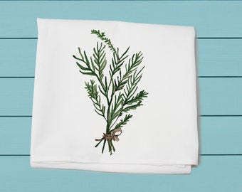 May include: A white kitchen towel with a green watercolor illustration of a bunch of leafy sprigs tied together with a brown twine.