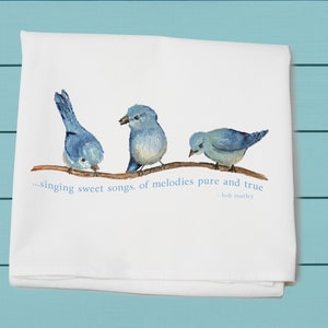 May include: A white tea towel with three bluebirds perched on a branch. The text reads "...singing sweet songs, of melodies pure and true - Bob Marley"