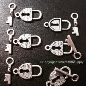 May include: Six silver-toned lock and key charms. Each charm features a detailed lock with a keyhole and a matching key. The charms are perfect for adding a vintage touch to jewelry or crafts.