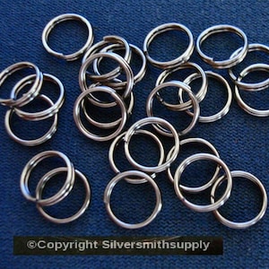May include: A close-up of a pile of silver jump rings. The rings are all the same size and are arranged in a random pattern. They are perfect for jewelry making or other crafts.