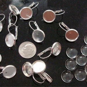 May include: A set of 10 silver earring settings with clear glass cabochons. The settings have a lever back closure. There are also 12 extra clear glass cabochons.