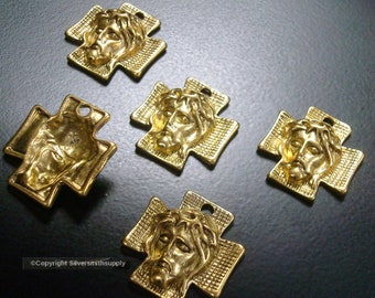 May include: Five gold-coloured metal cross charms with a raised image of Jesus' face on each. The crosses are approximately 2.5 cm in size.