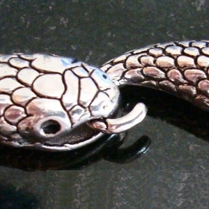 Può includere: Chiusura a scorrimento a testa di serpente in argento con un design testurizzato e squamoso. La chiusura è aperta e pronta per essere attaccata a una collana o un braccialetto.