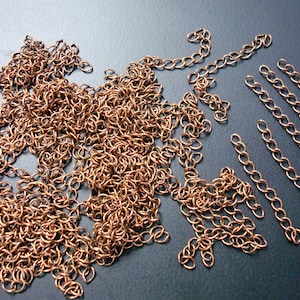 May include: A pile of copper chain links, some are loose and some are connected in short lengths.