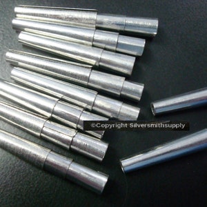 May include: A set of 10 silver metal tapered mandrels for jewelry making. The mandrels are arranged in a pile, with some of them overlapping. The mandrels are all the same size and shape, and they have a smooth, polished finish.