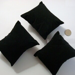 Puede incluir: Tres almohadas de reloj de terciopelo negro, ideales para exhibir relojes u otras joyas. Las almohadas son cuadradas y tienen una textura suave y mullida.