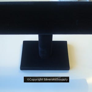 May include: Black velvet bracelet display stand with a square base and a cylindrical rod.