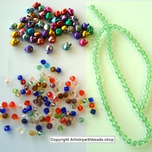 May include: A collection of colorful craft beads and bells. The image shows a variety of small, metallic bells in shades of gold, pink, purple, and green. There are also faceted beads in various colors, and a strand of light green beads.