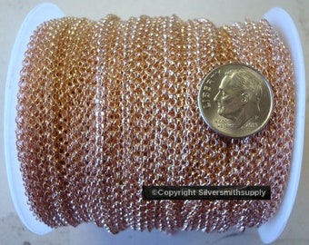 May include: A spool of rose gold colored chain, next to a US dime for scale. The chain is made of small, linked circles.