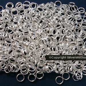 May include: A large pile of silver jump rings. The rings are all the same size and are arranged in a random pattern.  ©Copyright Silversmithsupply