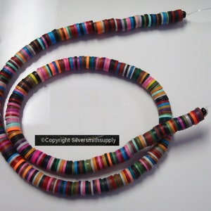 May include: A strand of colorful round beads, each bead is a different color and has a flat, circular shape. The beads are strung on a clear thread and are arranged in a random pattern.  The beads are approximately 1/2 inch in diameter.