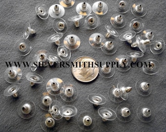 May include: A close-up of a pile of silver earring backs with clear plastic backs. The backs are designed to be used with post earrings.