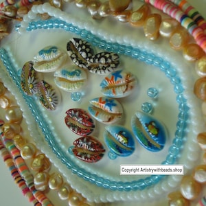 Puede incluir: Una colección de conchas de cauri pintadas y collares de cuentas de varios colores. Las conchas presentan diseños pintados a mano en rojo, azul y blanco. Los collares incluyen cuentas blancas, azul claro y multicolores. Copyright Artistrywithbeads.shop.