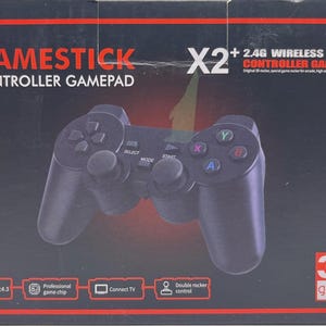 Może przedstawiać: Czarny kontroler GameStick w opakowaniu. Na pudełku widnieje napis „GAMESTICK CONTROLLER GAMEPAD” oraz „X2 + 2.4G WIRELESS CONTROLLER GAMEPAD”. Pad ma przyciski z literami i symbolami, a na pudełku widnieje napis „3D games”.