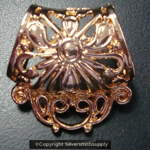 Könnte beinhalten: Goldfarbener Schmuckverschluss aus Metall mit einem dekorativen Blumenmuster. Der Verschluss ist halbkreisförmig und hat ein zartes, filigranes Muster.