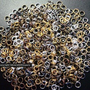 May include: A large pile of mixed metal jump rings in silver, gold, and bronze. The jump rings are all the same size and are perfect for jewelry making.